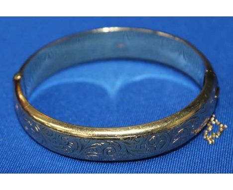 NINE CARAT GOLD BANGLE
with engraved scrolling decoration, marked 375, 17g