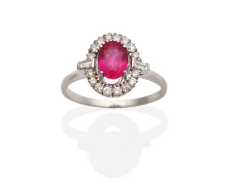 An 18 Carat White Gold Ruby and Diamond Cluster Ring, an oval cut ruby in a claw setting, within a border of round brilliant 