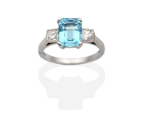 An 18 Carat White Gold Aquamarine and Diamond Three Stone Ring, an octagonal cut aquamarine in a claw setting, spaced by prin