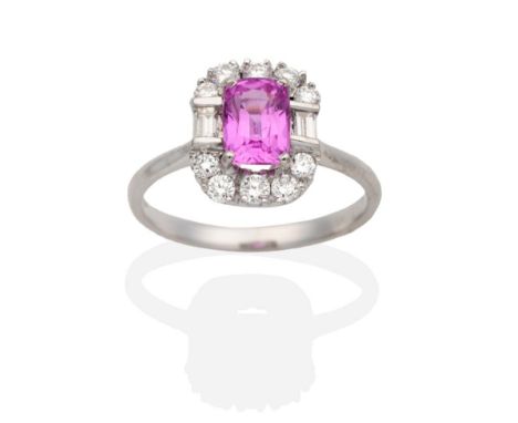 An 18 Carat White Gold Pink Sapphire and Diamond Cluster Ring, a cushion cut pink sapphire in a claw setting, within a border