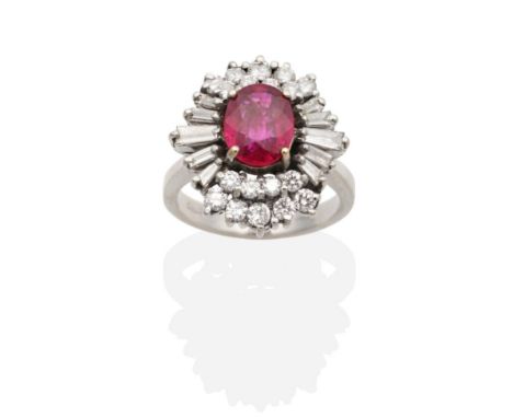 A Ruby and Diamond Cluster Ring, an oval cut ruby in a claw setting, within a two tier border of round brilliant cut and tape