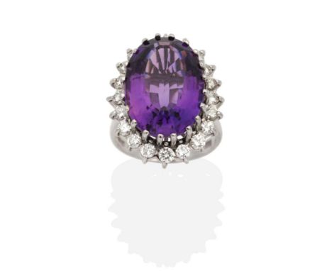 An 18 Carat White Gold Amethyst and Diamond Cluster Ring, an oval cut amethyst in a claw setting, within a border of round br
