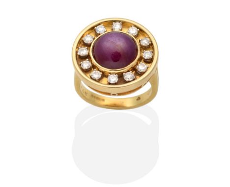 An 18 Carat Gold Star Ruby and Diamond Cluster Ring, a round cut star ruby in a rubbed over setting, within a circular frame 