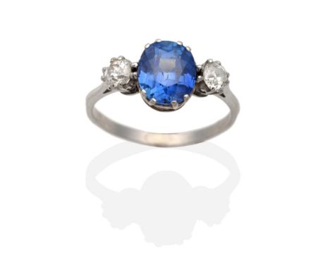 A Sapphire and Diamond Three Stone Ring, an oval cut sapphire in a double claw setting, between old cut diamonds, to knife ed