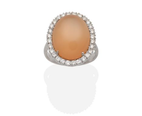 An 18 Carat White Gold Moonstone and Diamond Cluster Ring, an oval cabochon peach moonstone within a border of round brillian