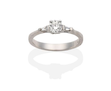 A Platinum Diamond Ring, a round brilliant cut diamond between tapered baguette cut diamonds, in claw settings, total estimat