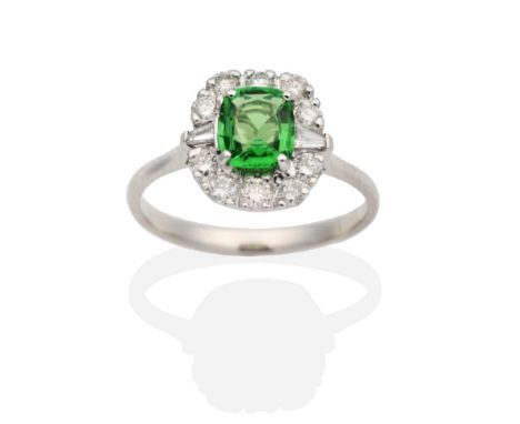 An 18 Carat White Gold Green Garnet and Diamond Cluster Ring, a cushion cut green garnet in a claw setting, within a border o
