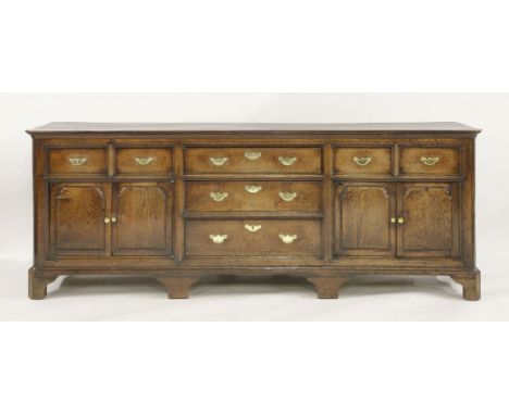 A George III oak dresser base,the planked top over a central bank of three drawers, flanked by two short drawers over panelle