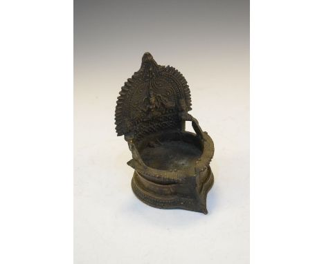 Indian or South East Asian alloy votive oil lamp, the back modelled in relief with a seated deity over oil reservoir, 13cm hi