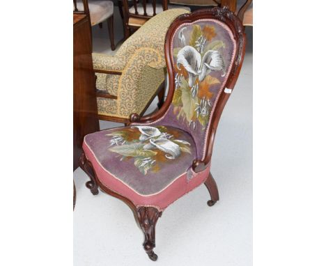 A Victorian mahogany spoon back nursing chair on cabriole front legs and castors covered in needlepoint floral design 