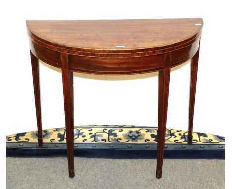 A George III cross banded mahogany demi-lune fold over card table 90cm by 44cm by 74cm.  The top is faded with staining marks