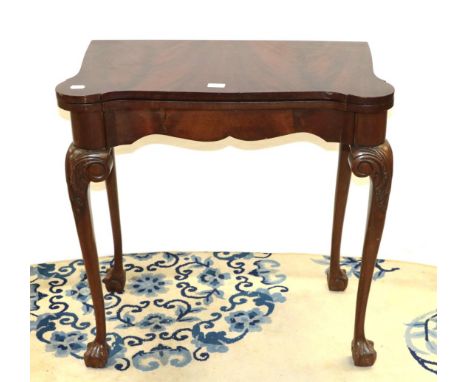 An early 20th century mahogany fold over card table on ball and claw feet