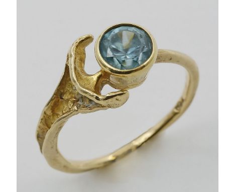 Damenring. 750/000 GG, brutto 3,1 g. Rustikal gearbeitete Fassung, besetzt mit rund facettiertem, blauen wohl Zirkon. R 53.