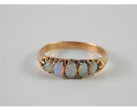 An opal set dress ring, with five graduated oval stones, set in yellow metal stamped 18c, 2.3g all in.