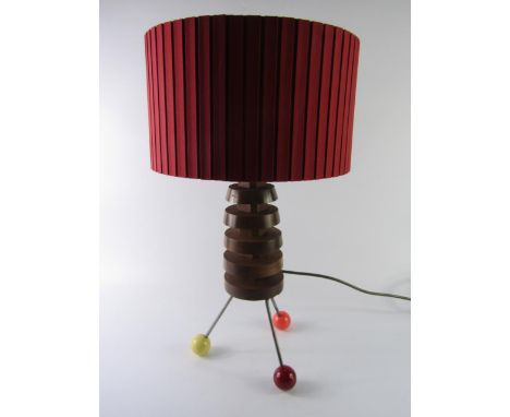 An Atomic style mid 20thC table lamp, turned wood raised on three metal rods and coloured ball feet, with shade, 53cm high.