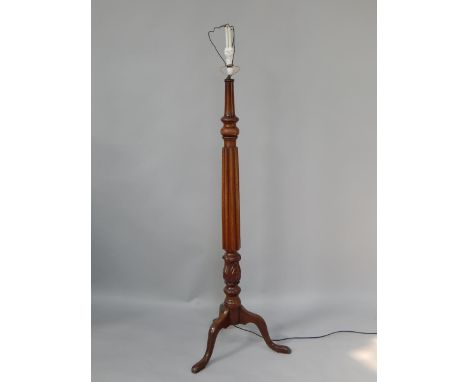 A Victorian mahogany standard lamp, converted to electricity, with a turned, fluted and leaf carved column, raised on three c