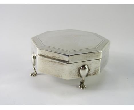 A George V silver jewellery box, of octagonal form with engine turned decoration, reserve monogram, silk lined, raised on fou