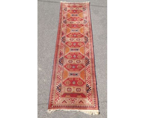 A Tekke design carpet runner, red ground with orange and blue Boteh, 307cm x 77cm.