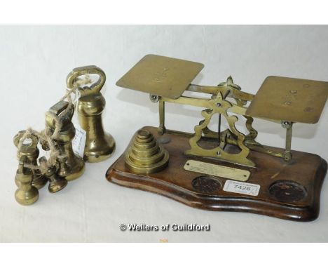 A set of brass and mahogany postal scales with five stacking weight; a set of seven brass bell weights, the largest 2lb.