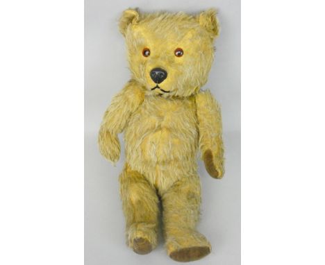 An early playworn beige teddy bear, with brown button eyes and jointed limbs, height 37cm.