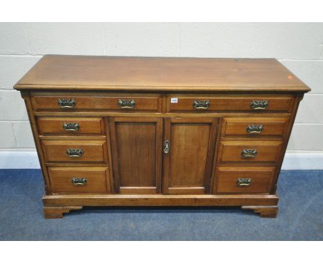 AN EARLY 20TH CENTURY SIDEBOARD, fitted with eight assorted drawers, and double cupboard doors, on bracket feet, length 141cm