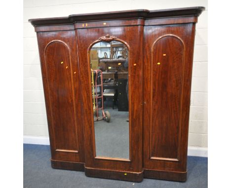 A VICTORIAN MAHOGANY TRIPLE DOOR BREAK FRONT COMPACTUM WARDROBE, the central mirrored door enclosing linen slides and drawers