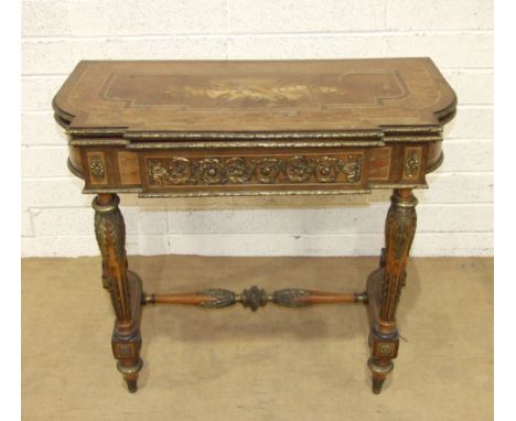 A late Victorian fold-over card table in the French taste, the marquetry top decorated with musical instruments and lattice w