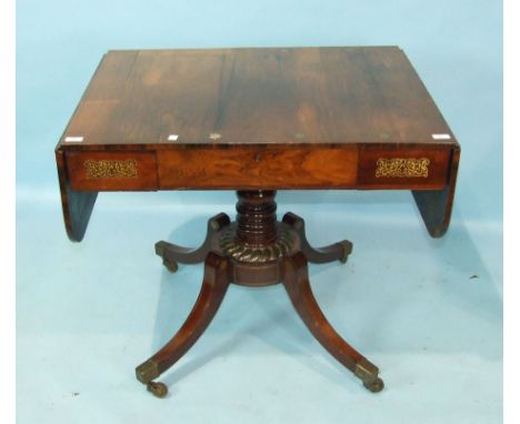 A Regency sofa table, the rectangular top with two drop leaves inlaid with brass lines and star motifs above a central frieze