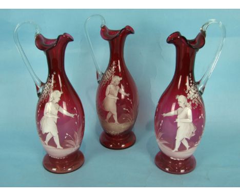 A set of three 19th century English ruby glass ewers painted in Mary Gregory style with children playing, 26cm high, (3).