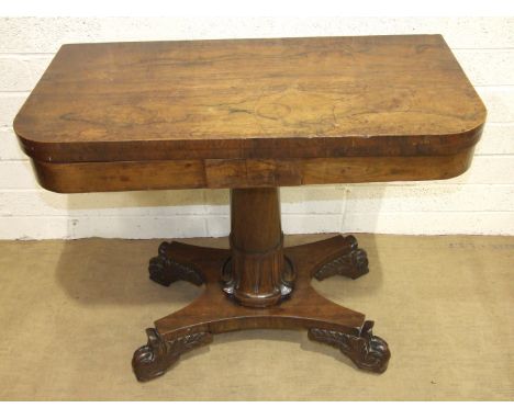 A George IV rosewood fold-over card table, the rectangular top on a tapered and carved column and concave platform, with leaf