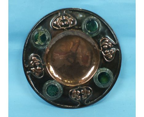 An Art Nouveau circular heated copper dish with embossed decoration and applied Ruskin-style ceramic plaques, 30cm diameter.