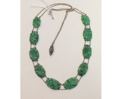 A necklace of ten graduated carved jade oval plaques, each joined to the next by pairs of yellow metal chains, with marcasite
