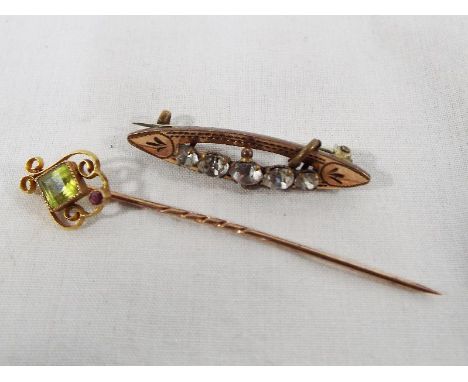 A lady's yellow metal tie pin with gilded detailing set with peridot and ruby, stone set and a yellow metal bar brooch with 9