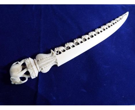 A 19th century highly carved ivory paper knife with a bridge of filigree elephants and elephant finial, overall length 23 cm 