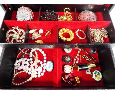 A faux leather jewellery box containing a small quantity of costume jewellery to include brooches, cultured pearls, enamelled