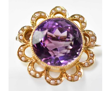 An early 20th century amethyst, seed pearl and gold brooch, the bezel set amethyst within an open scrolling border set with t