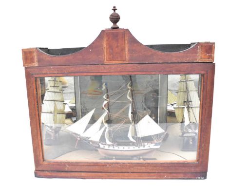 A small wooden model of Mercury, a two-masted ship, in display case with painted back and curved mirrored sides, case 46 x 18