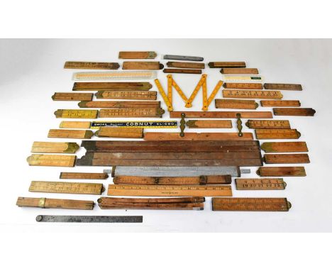 A quantity of vintage rulers and measuring sticks, to include mainly wooden examples, some steel and brass rules, a wooden fo