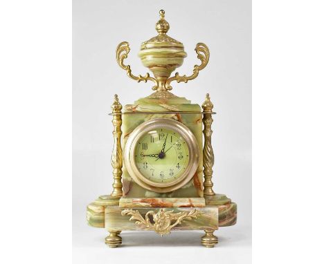 A green marble mantel clock, the enamelled dial set with Arabic numerals flanked by brass-effect columns, surmounted by a twi