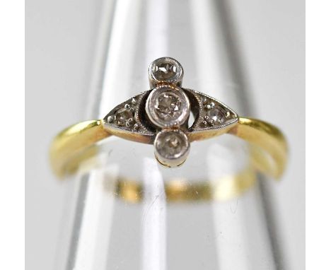 An A18ct gold Art Deco ring with three small bezel set diamonds flanked by smaller diamonds to the platinum mount shoulders, 