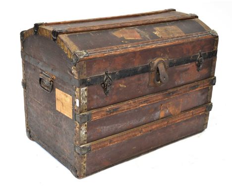 An early 20th century leather dome-topped brass bound travel trunk with wooden slats and steel furniture, with traces of trav