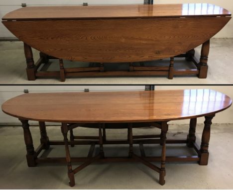 A solid oak Wake table. Long rectangular top flanked with oval drop leaves. Turned supporting legs and gate legs with a box s