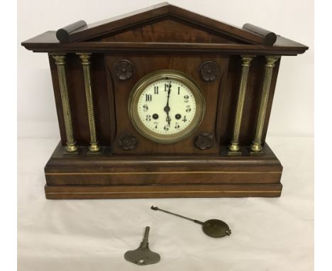 A vintage mahogany cased mantle clock with brass column detail. Ceramic base, complete with key and pendulum. 32.5cm tall x 4