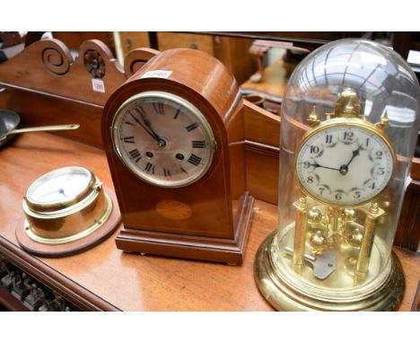 An Edwardian mahogany and inlaid dome top mantel clock, 27cm high; together with a brass anniversary clock with glass dome; a