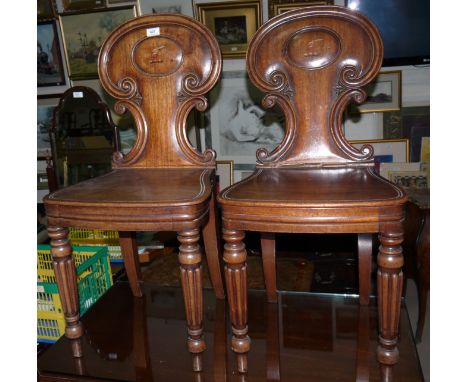 A pair of early 19th century mahogany hall chairs with oval crested panel backs, solid seats and reeded legs (a.f.)