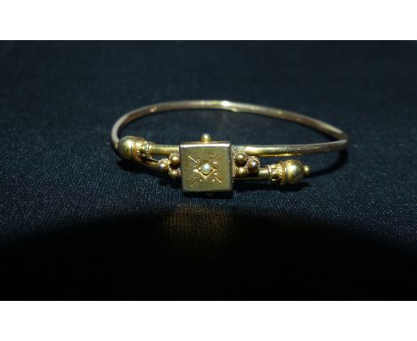 An Edwardian child's bangle set with a seed pearl, stamped '9CT', 34 gm