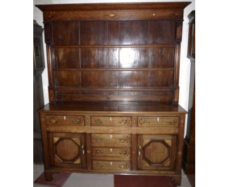 An 18th century oak country made Welsh dresser with geometric inlaid motifs, having 3 height Delft rack over 3 frieze and 3 c