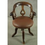 An Edwardian fruitwood swivel desk chair, with a curved back and heart pierced splat, over a