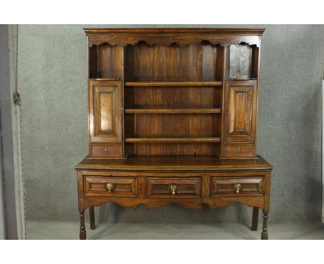 An 18th century country dresser, with three shelves flanked by two panelled cupboard doors and two short drawers, over three 