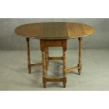 An early 20th century oak drop leaf table, the oval top with a moulded edge, on turned gatelegs,